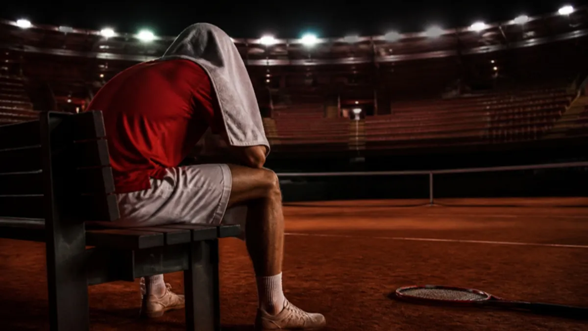 Emotionen im Sport: Tennisspieler mit Handtuch über dem Kopf auf der Bank beim Seitenwechsel