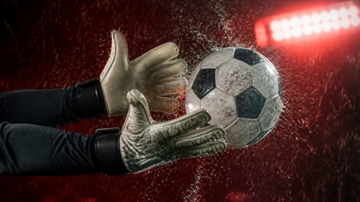 Fußball bei Regen: Torwart-Handschuhe am nassen Ball, Wasser spritzt