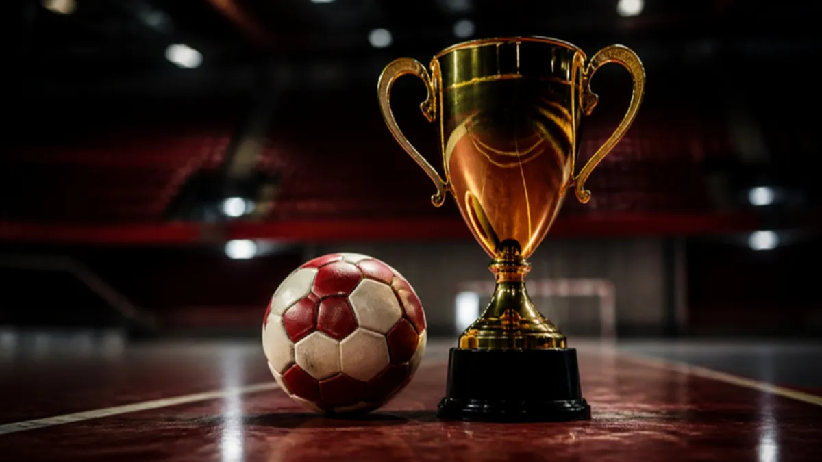 Handball WM 2027: Pokal neben einem Handball auf dem Hallenboden