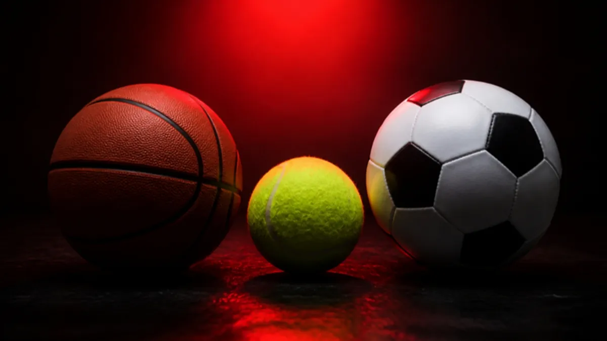 Sportwetten-Begriffe: Basketball, Tennisball und Fußball unter rotem Spotlicht