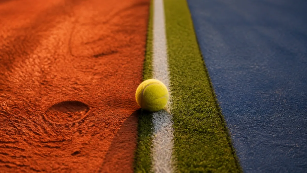 Tennis Wetten Strategie: Tennisball an der Grenze von Sand, Rasen und Hartplatz
