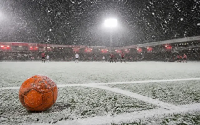 Wetter beim Fußball: oranger Winterball auf schneebedecktem Platz im Flutlicht