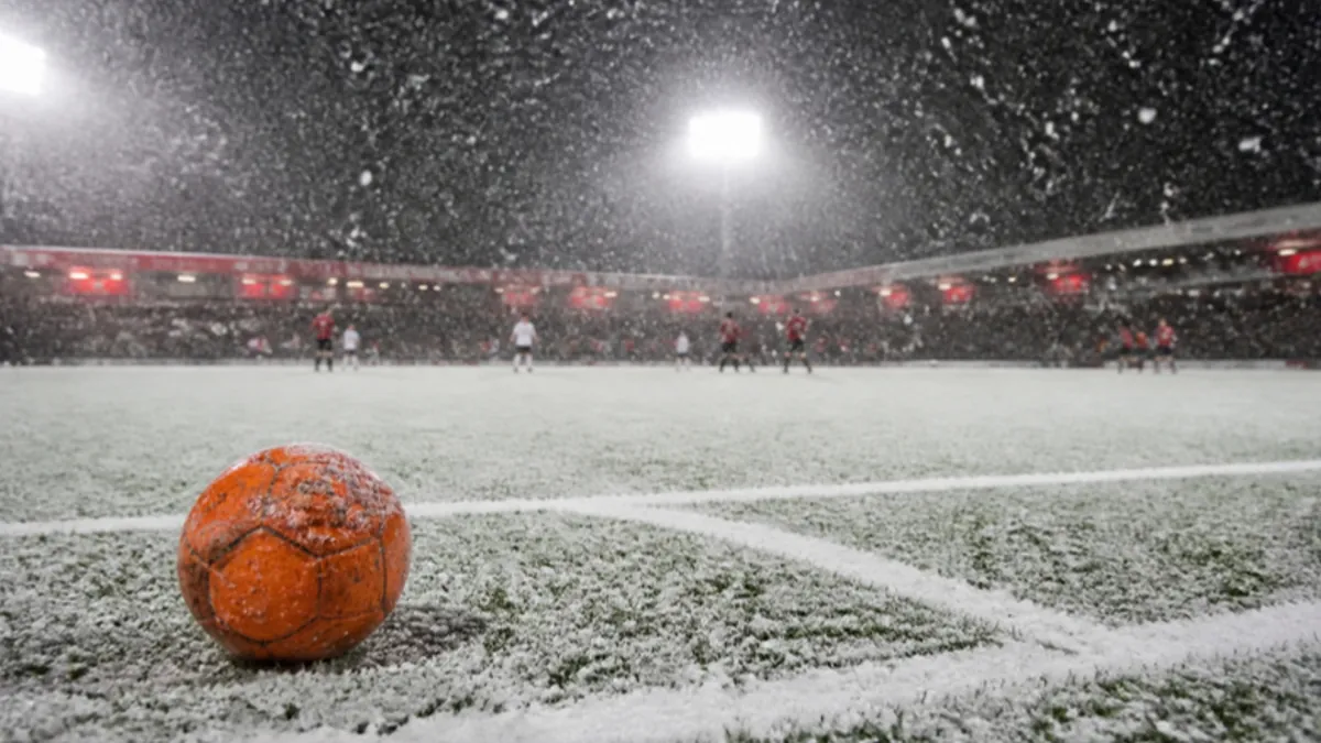 Wetter beim Fußball: oranger Winterball auf schneebedecktem Platz im Flutlicht
